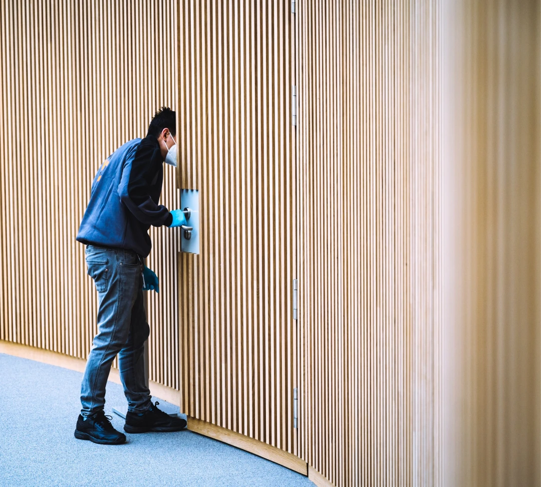 Agent de nettoyage désinfectant une poignée de porte avec masque et gants de protection